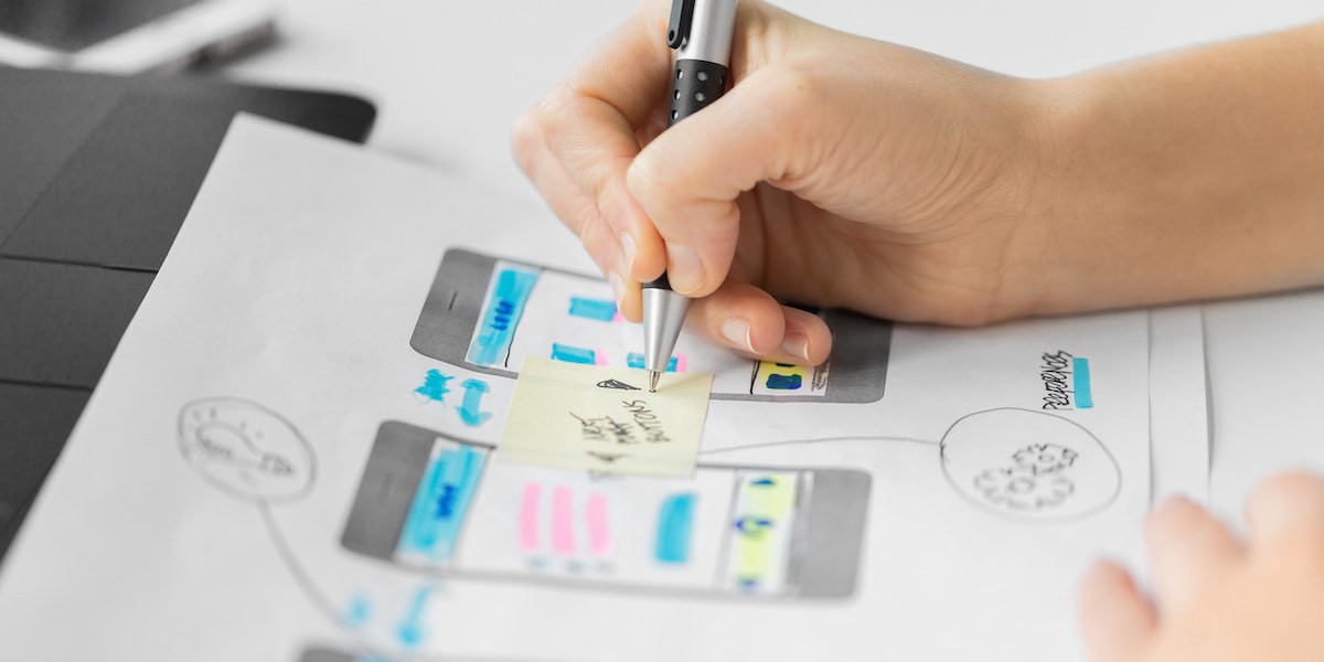 Person designing screens by hand on paper